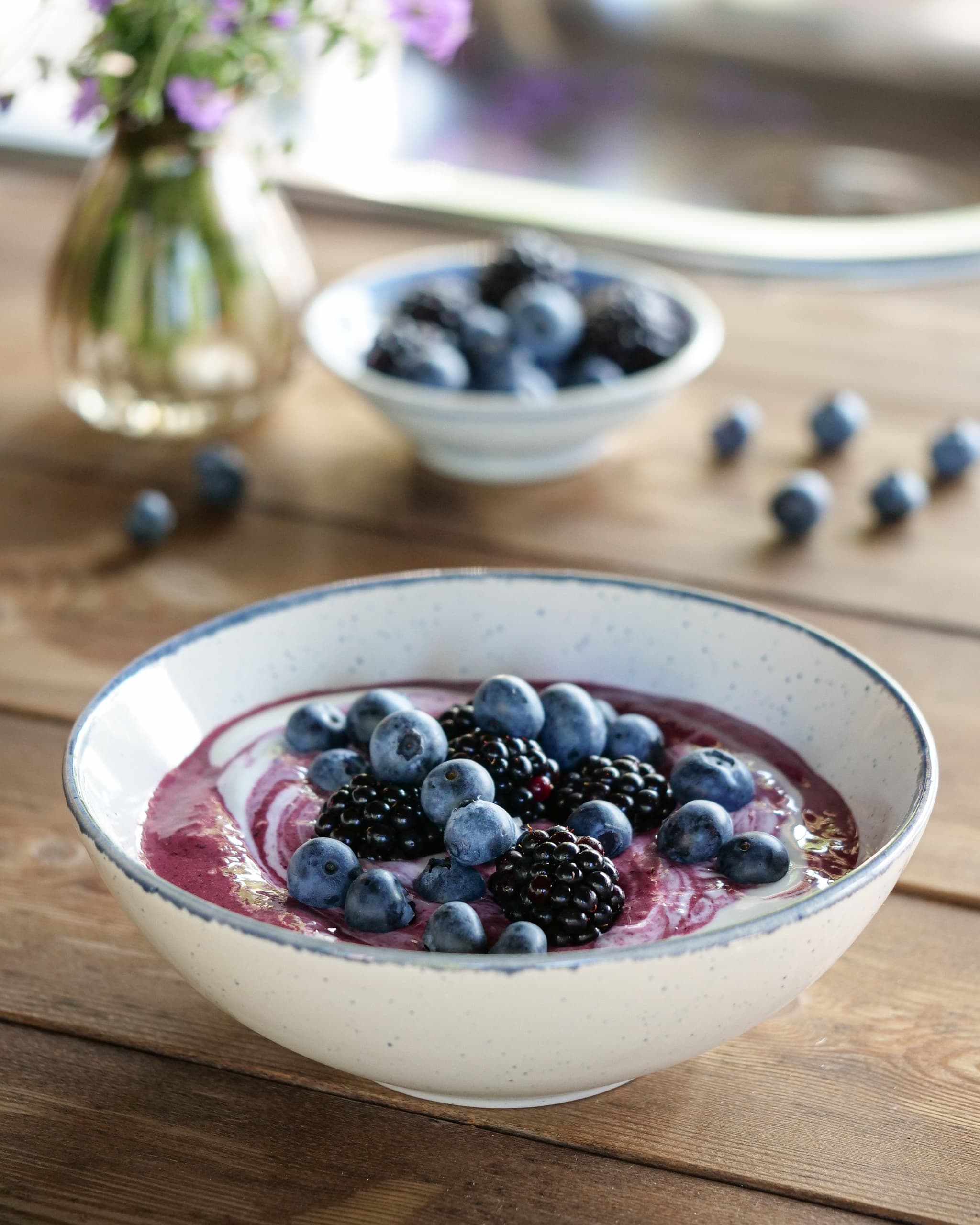 En skål smoothiebowl med blåbær og bjørnebær på toppen